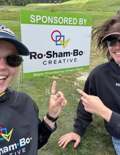 Sam and Vincent in front of RoShamBo Creative sign at Kieffer Golf Tournament